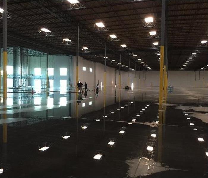 Large warehouse with lights and standing water.